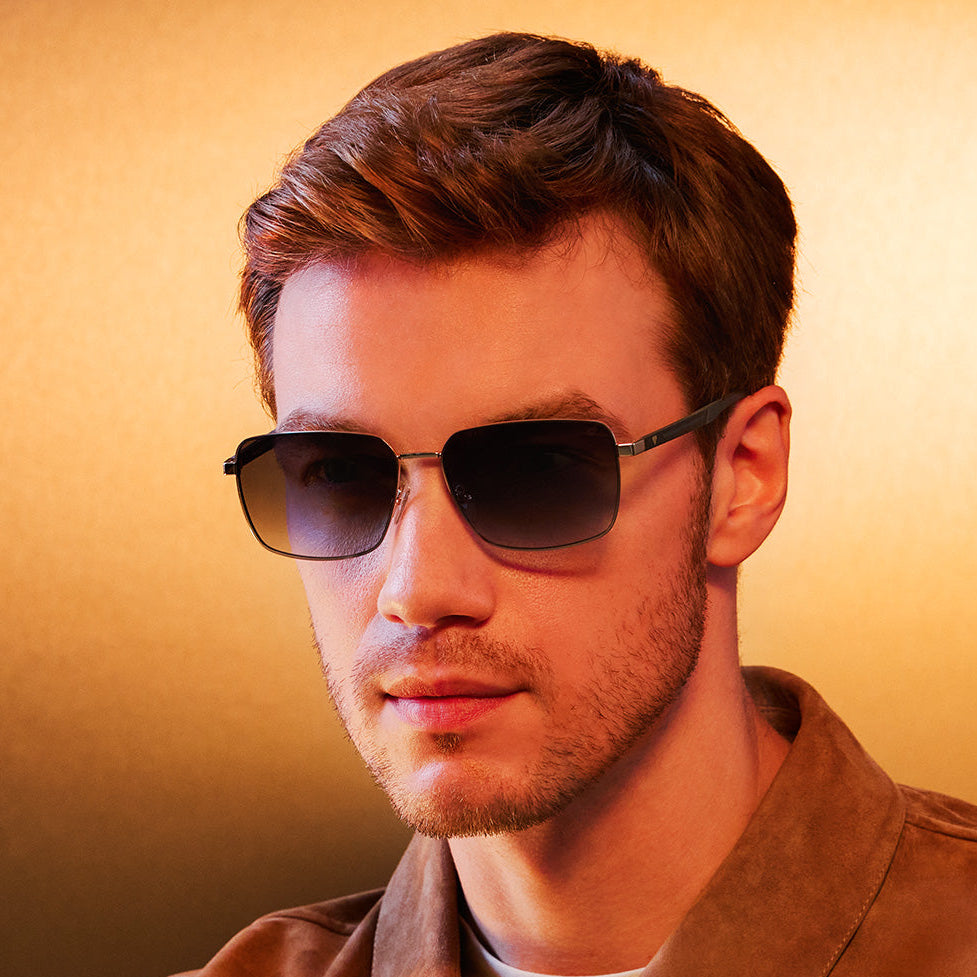 Man wearing sunglasses with 'Blancia Milano' branding on a warm-toned background